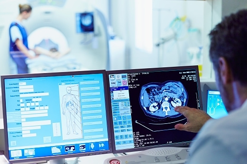 Male doctor running CT scan from control room at hospital